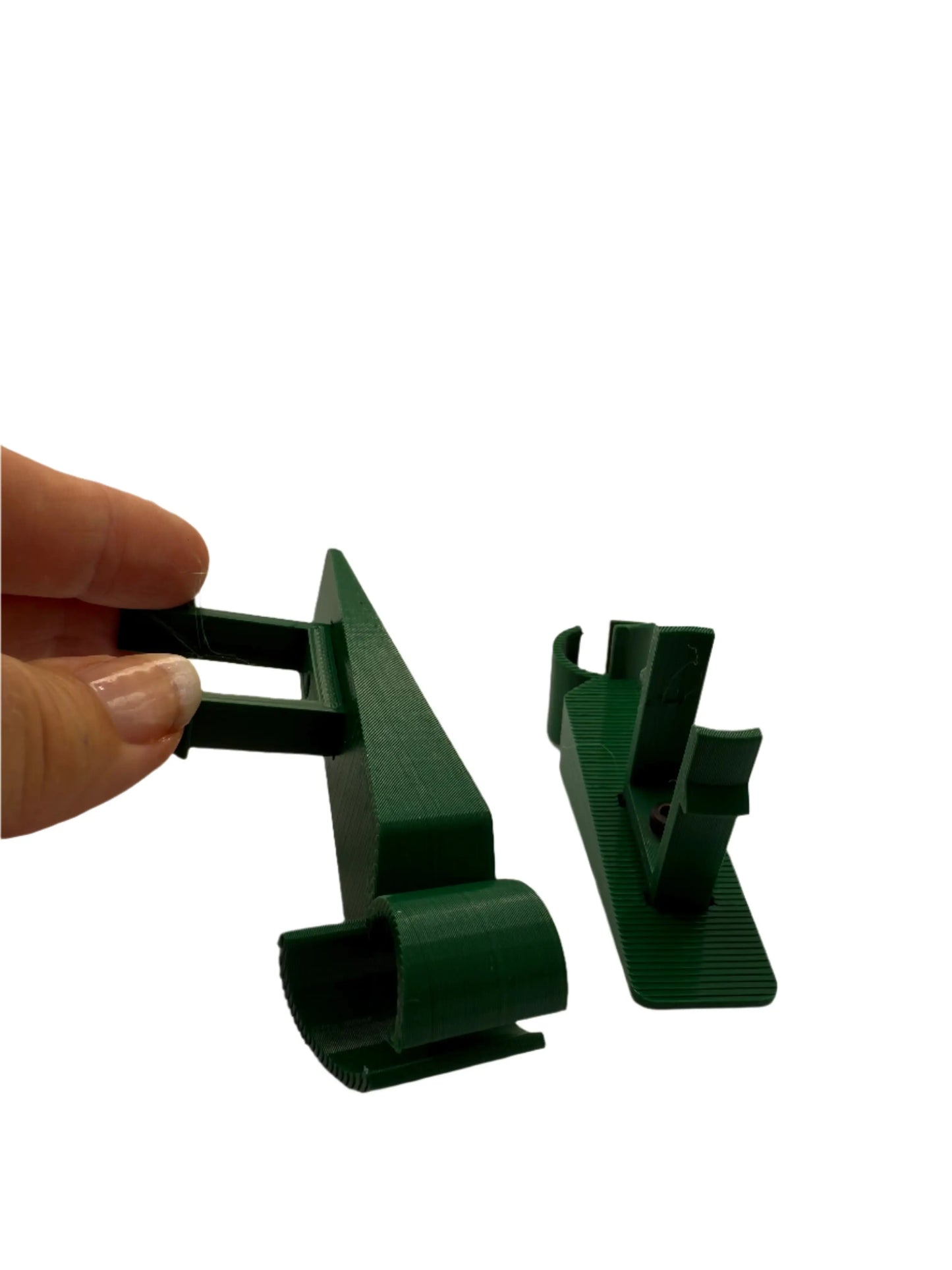 Hand holding green 3D printed plastic clip next to another on white background