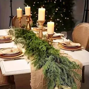 Elegant holiday dining table with gold candlesticks, evergreen garland, and festive decor