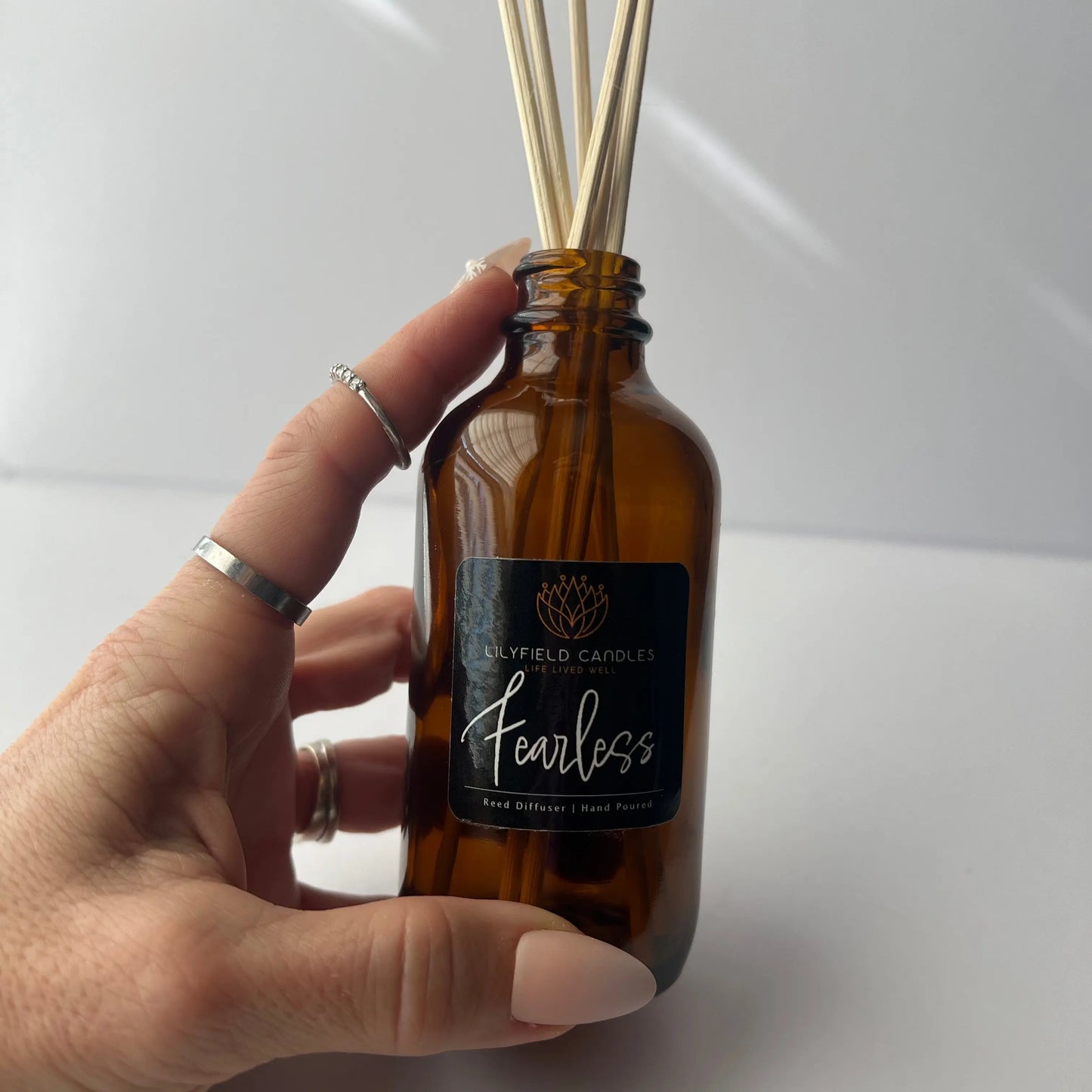 Hand holding Lilyfield Candles Fearless reed diffuser in amber glass bottle